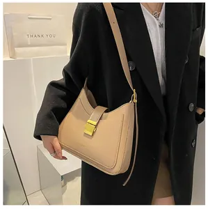 Detail of a beige PU leather bucket bag with gold metal buckle shown on a female model