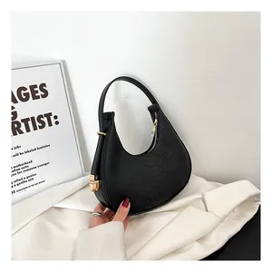 Detail of black croco-effect crescent shoulder bag featuring gold metal hardware accents
