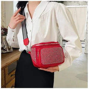 Détail d'un sac ceinture rouge à strass avec bandoulière tissée noire et blanche