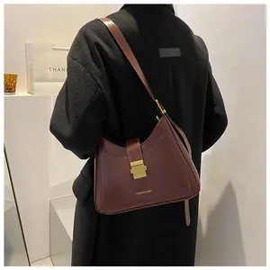 Detail of burgundy vintage bucket bag with gold buckle and fashion text on shoulder