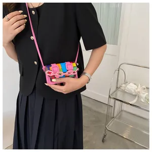 Macro detail of mini crossbody bag with colorful geometric mosaic patterns and pink chain