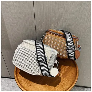 Détail de sacs à bandoulière en strass avec larges sangles à motifs sur un tabouret