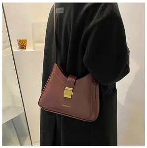 Fashionable burgundy leather bucket bag with gold clasp shown on a shoulder