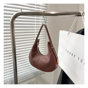 Detail of brown crocodile pattern half-moon shoulder bag with golden zipper and hardware
