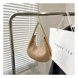 Close-up of beige hobo bag with crocodile texture hanging on a metal hook