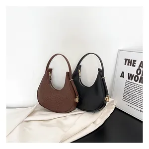 Detail shot of brown and black crescent underarm bags with premium crocodile texture