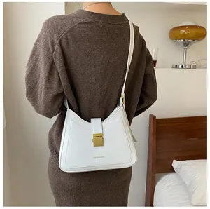 Rear view of a white crescent hobo bag with a gold buckle worn on the shoulder