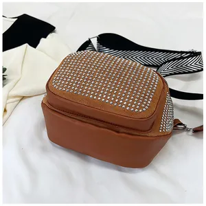 Détail du sac bandoulière marron avec rivets argentés et sangle tissée à chevrons