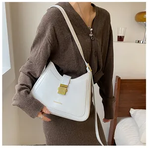 Close-up of minimalist white leather bucket bag with gold metal buckle and fashion logo