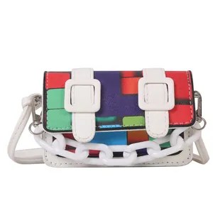 Detail of colorful geometric print crossbody bag with white chain and buckle accents