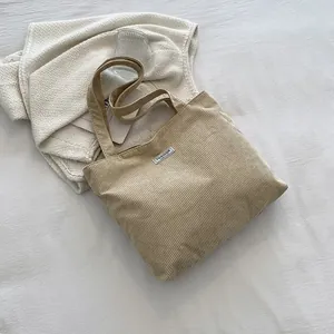 Detail of a corduroy tote bag featuring a Fashion label on a soft fabric background