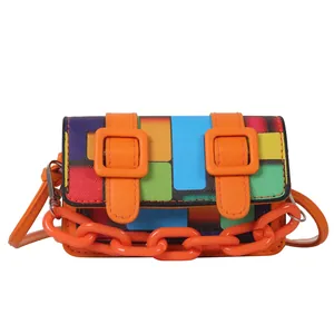 Close-up of vibrant mosaic pattern crossbody bag with orange straps and chain detail