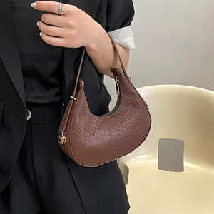 Brown crocodile pattern half-moon hobo bag with sleek shoulder strap on a model