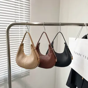 Three crocodile pattern underarm bags in khaki, brown, and black displayed on stands