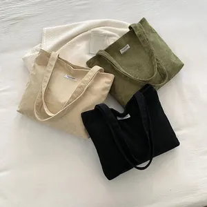 Detailed view of beige, green, and black corduroy tote bags with soft texture and fashion labels