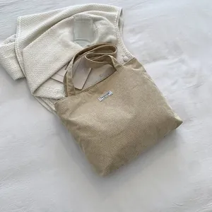 Close-up of beige corduroy tote bag texture and white FASHION tag in aesthetic setting