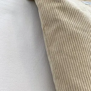 Close-up of beige corduroy fabric texture and white fashion label on a shoulder bag