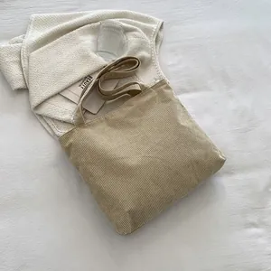 Detailed macro view of the corduroy fabric texture and stitching on this khaki tote bag