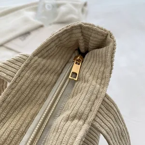 Detailed close-up of a durable gold metal zipper on a cream corduroy tote bag