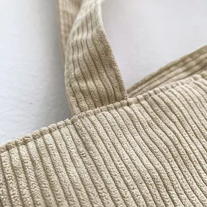Close-up of reinforced stitching on beige corduroy shoulder bag straps