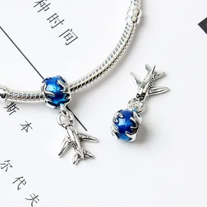 Detail of travel charm bracelet with blue enamel globe and silver airplane pendant