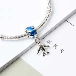 Close-up of silver airplane pendant and blue enamel globe bead on a snake chain