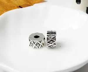 Macro view of antique silver spacer beads with engraved cross patterns for DIY bracelets