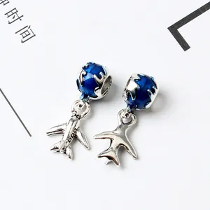 Detailed close-up of a silver airplane charm and blue enamel globe pendant for bracelets