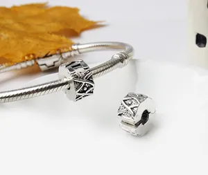 Macro shot of vintage silver flower charms with intricate geometric engraving on a snake chain