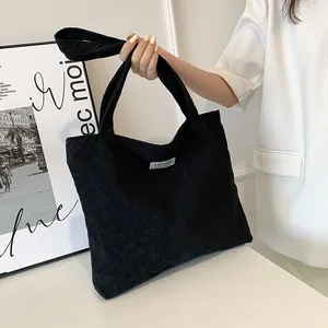 Detail of black corduroy tote bag showing 'FASHION' label and soft textured fabric