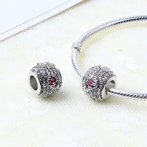 Macro shot of silver heart charm with pink stone and white crystals on a snake chain