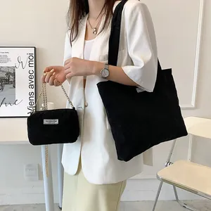 Detail view of black corduroy tote bag set with metal chain and Fashion label logo