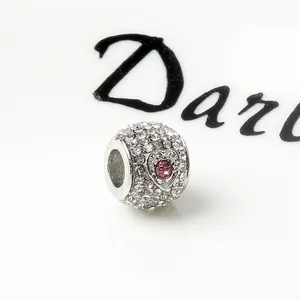 Silver charm bead with pavé crystals and a pink round center stone in a heart frame