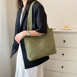 Olive green corduroy tote bag showing side view with wide shoulder strap and fabric label