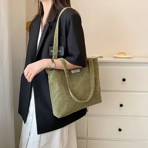 Close-up of olive green corduroy tote bag featuring vertical stripes and fashion label