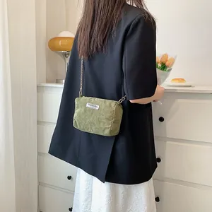 Close-up of green corduroy crossbody bag with gold chain strap and FASHION label