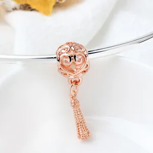 Macro shot of rose gold heart charm with hollow pattern and small metal tassel detail