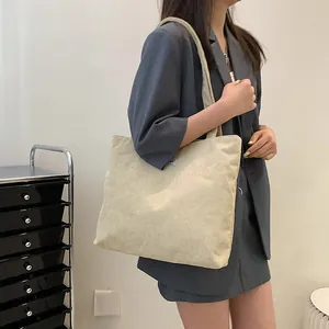 Close-up of beige corduroy tote bag showing ribbed texture and shoulder strap details