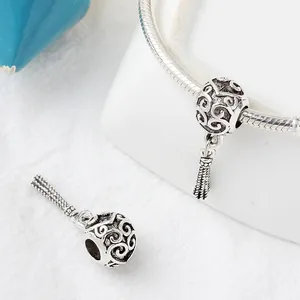 Detail of vintage silver hollow bead with tassel charm on a DIY charm bracelet