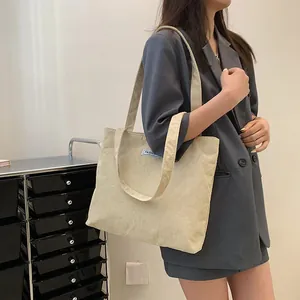 Detailed texture of off-white corduroy tote bag featuring a blue Fashion label on the side
