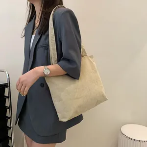 Spacious corduroy tote bag in beige shown on model for size and drape perspective