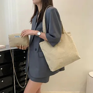 Detail view of beige corduroy tote and small clutch with elegant gold chain strap