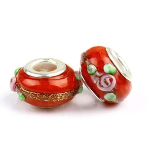 Close-up of red glass beads with gold glitter bands and green dots for bracelets