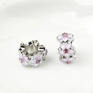 Macro detail of cherry blossom beads with pink enamel petals and a small central zircon