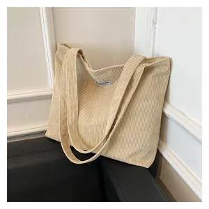 Detail of beige corduroy tote bag showing striped texture and Fashion woven label