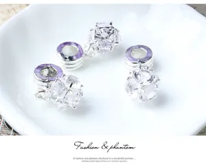 Detailed macro view of sparkling zircon pendants with silver charms on a white ceramic plate