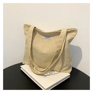 Detailed texture of beige corduroy tote bag with Fashion label on the black table