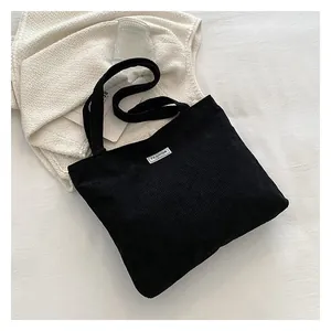Detail of black corduroy tote bag showing the fashion label on smooth fabric