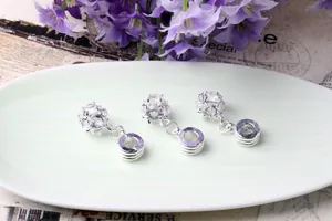 Three sparkling zircon crystal pendants on a ceramic plate for DIY jewelry making