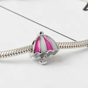 Macro-opname van een roze en witte emaille paraplu-bedel aan een zilveren slangenarmband